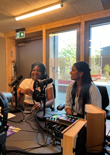 Two young people speaking in a recording studio space.
