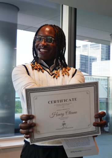 Young person smiling while holding graduation certificate